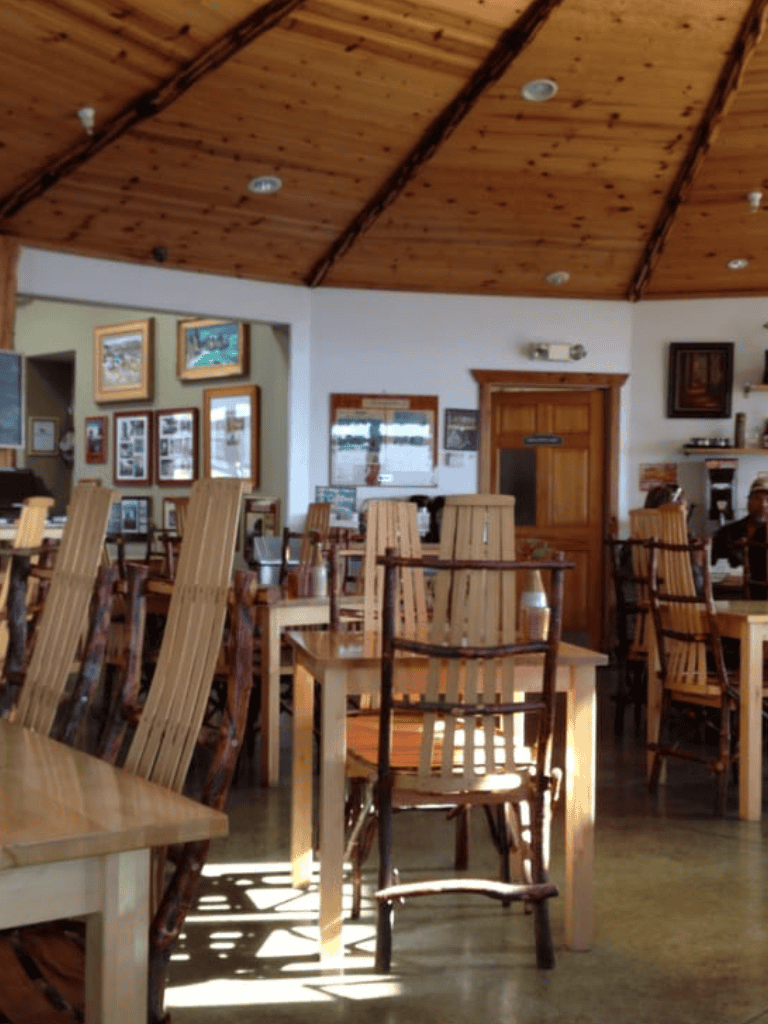 Wooden dining chairs and tables in cozy restaurant interior with framed pictures on wall.