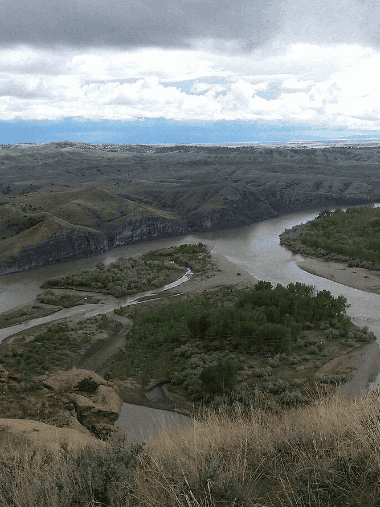 Vast river valley with winding water pathways amidst rolling hills and rugged terrain.