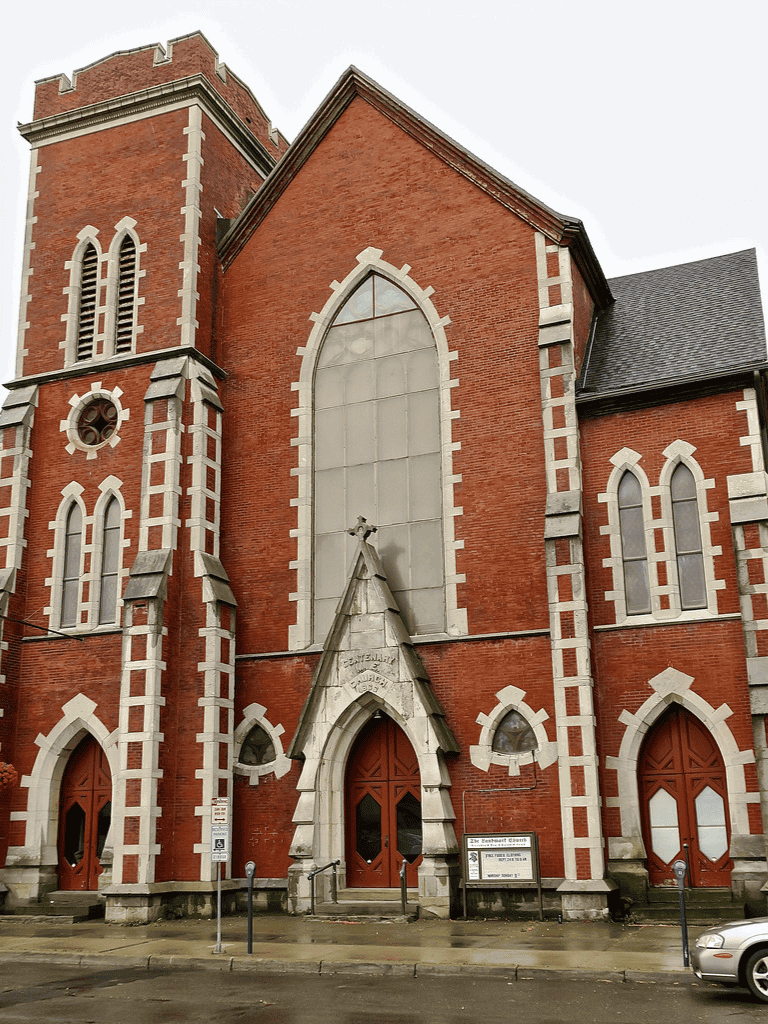 Old brick church with pointed arch windows and towers, located in downtown area.