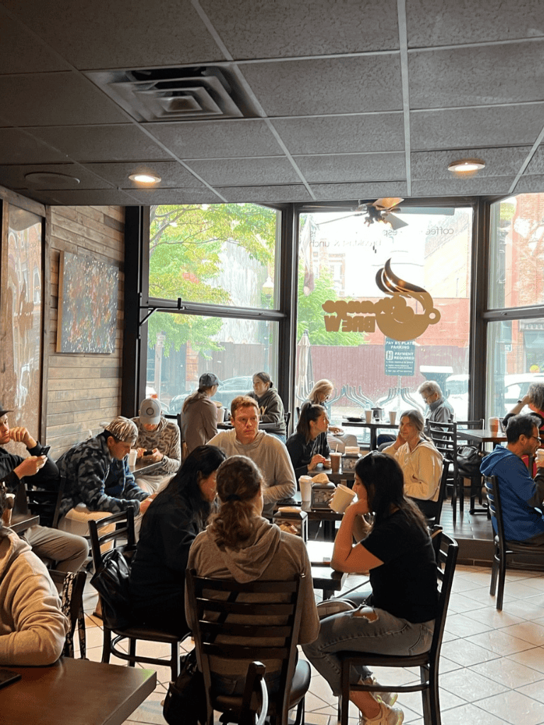 Quiet coffee shop interior with people dining and working, large front windows, casual atmosphere, QuestForDirections SEO.