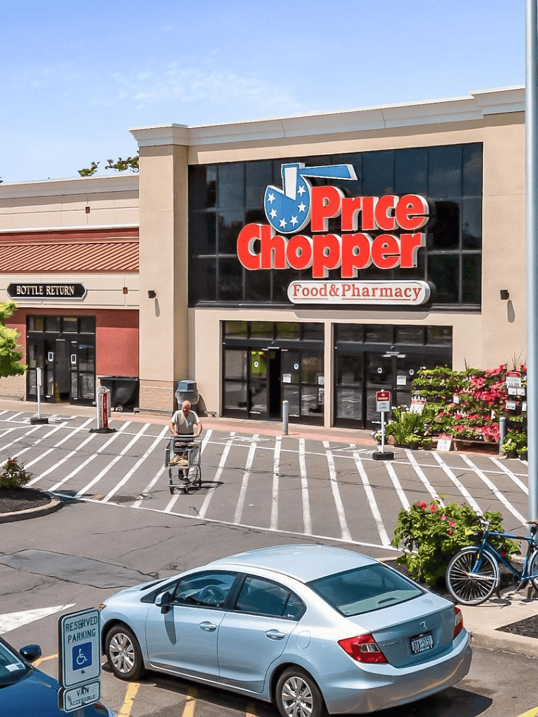 Price Chopper grocery store with parking lot and shopping cart, outside view.