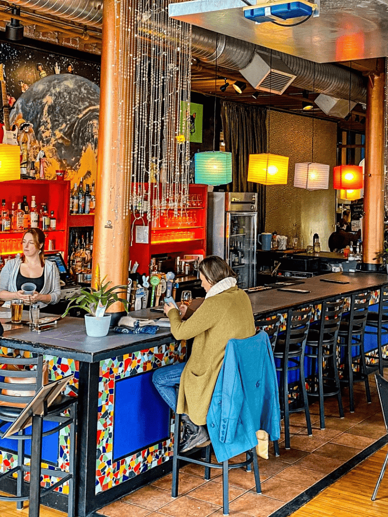 Enjoying cocktails at a colorful bar with modern decor and ambient lighting in a vibrant restaurant interior.