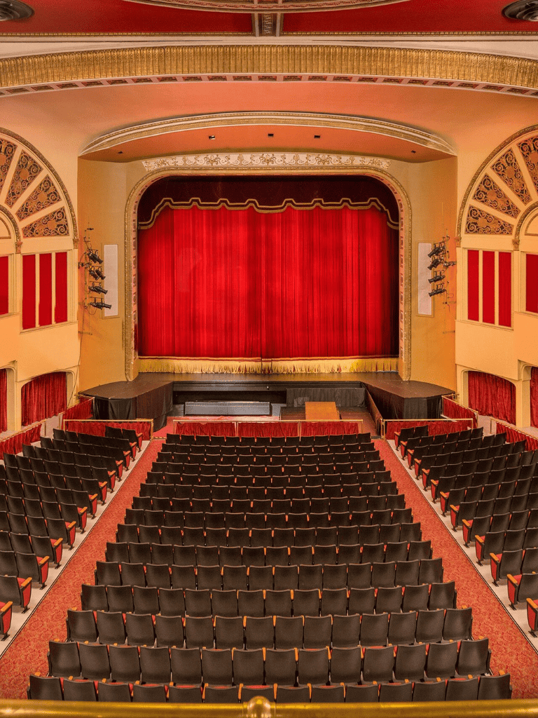 Elegant theater with red velvet curtains, plush seating, and ornate decor—ideal for live performances and cultural events.