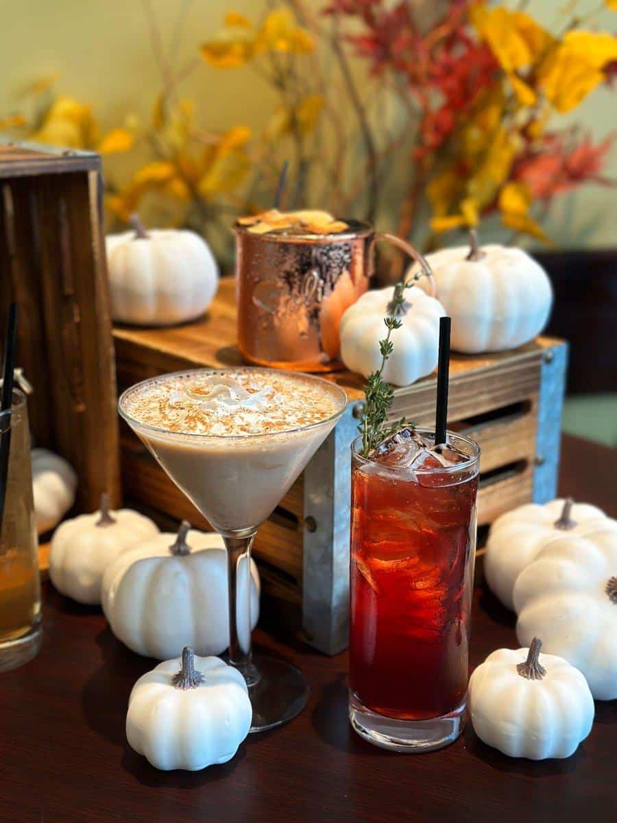 Elegant fall-themed cocktails with white pumpkins and autumn foliage, perfect for seasonal celebrations.