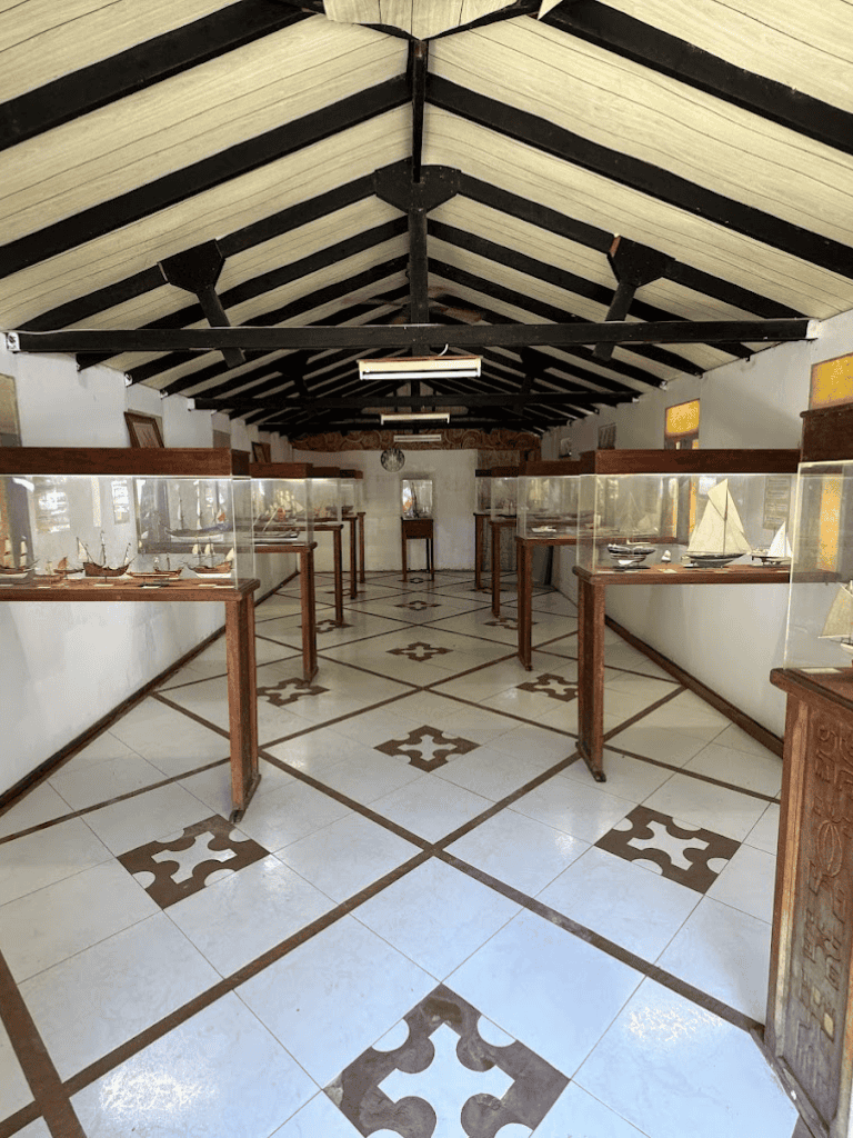 Ancient ship models display case at QuestForDirections maritime museum showroom, showcasing nautical artifacts and ship replicas.
