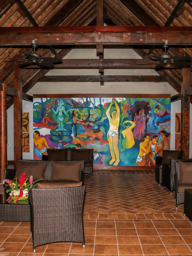 Vibrant cultural mural in tropical setting with seating area, evoking local artistry and relaxed ambiance.