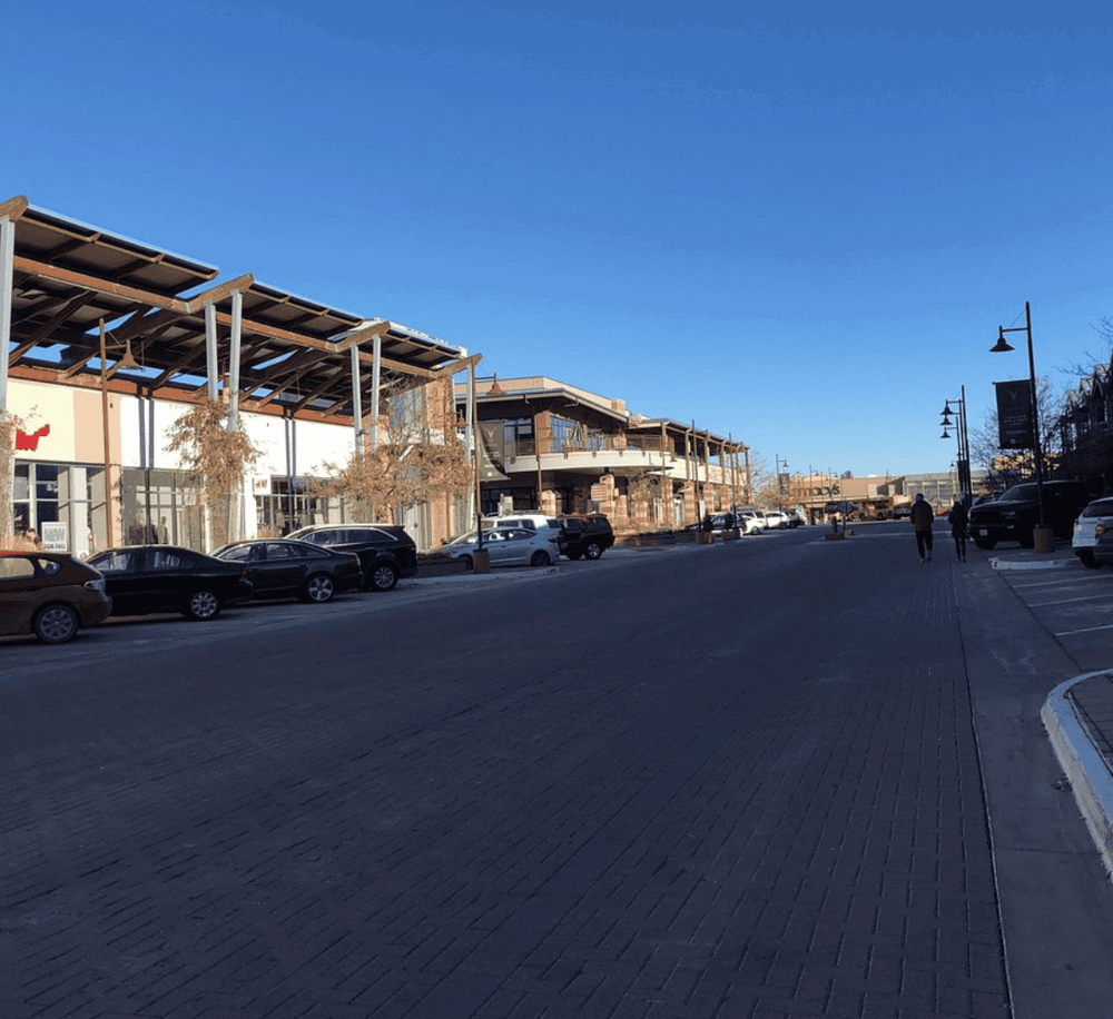 Modern shopping center exterior with parking lot and clear blue sky.
