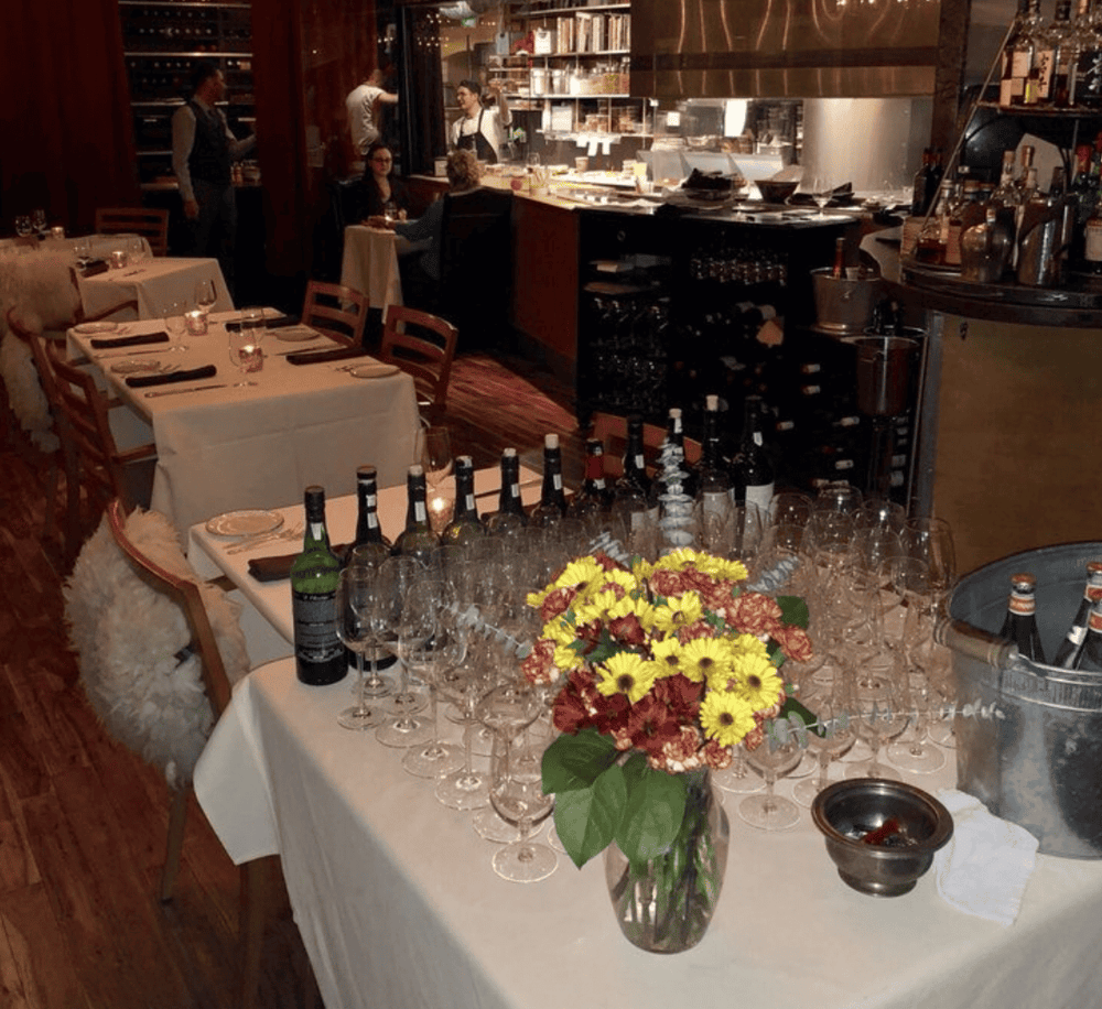 Elegant restaurant dining setup with wine bottles and floral centerpiece, perfect for fine dining experiences.