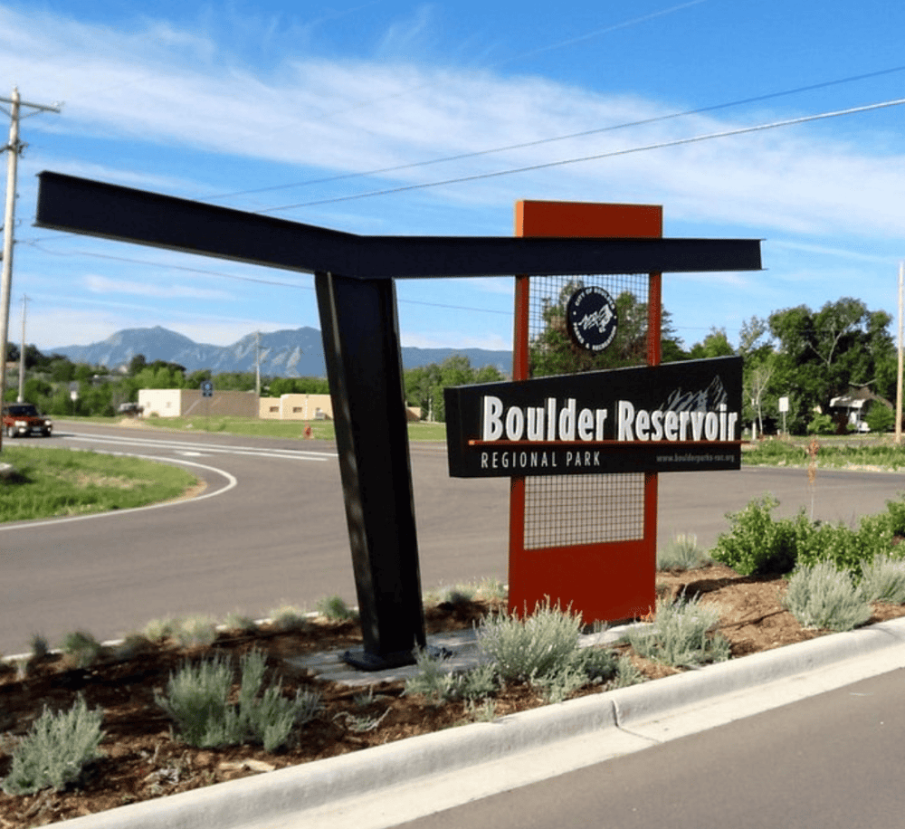 Modern Boulder Reservoir sign at regional park entrance with scenic mountain backdrop.