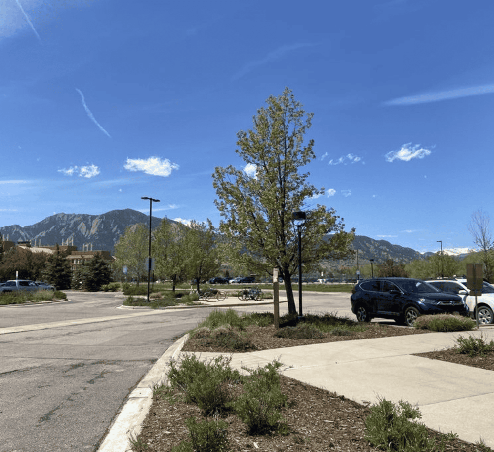 Bright parking lot with mountain views, trees, and clear blue sky, ideal for directions and navigation.
