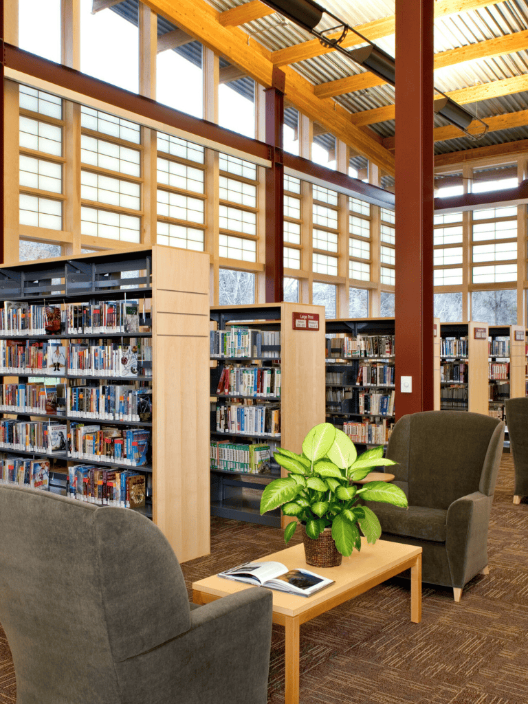1. Modern library interior with bookshelves, cozy seating, and natural light from large windows.