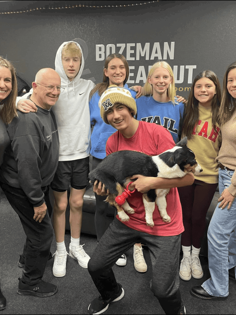 Happy group with a puppy at Quest for Directions in Bozeman, Montana, promoting community and pet adoption initiatives.