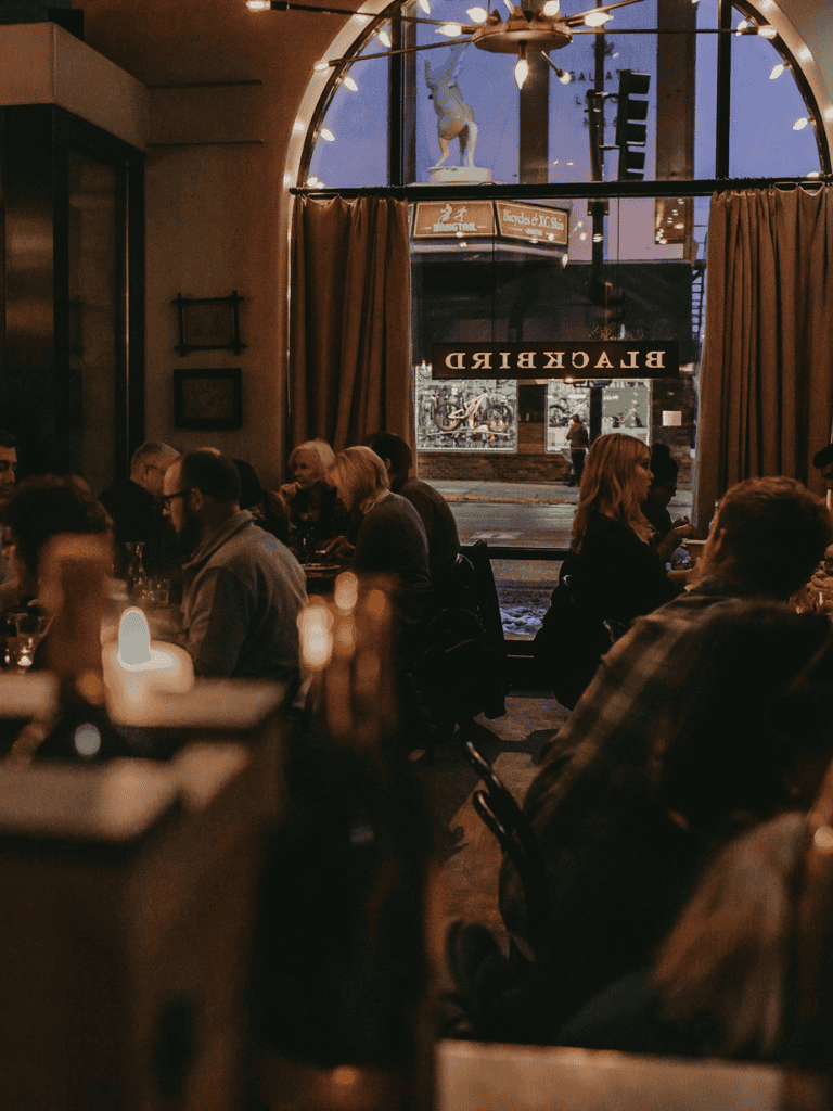 Cozy restaurant interior with dim lighting and diverse patrons enjoying dinner, showcasing inviting ambiance.