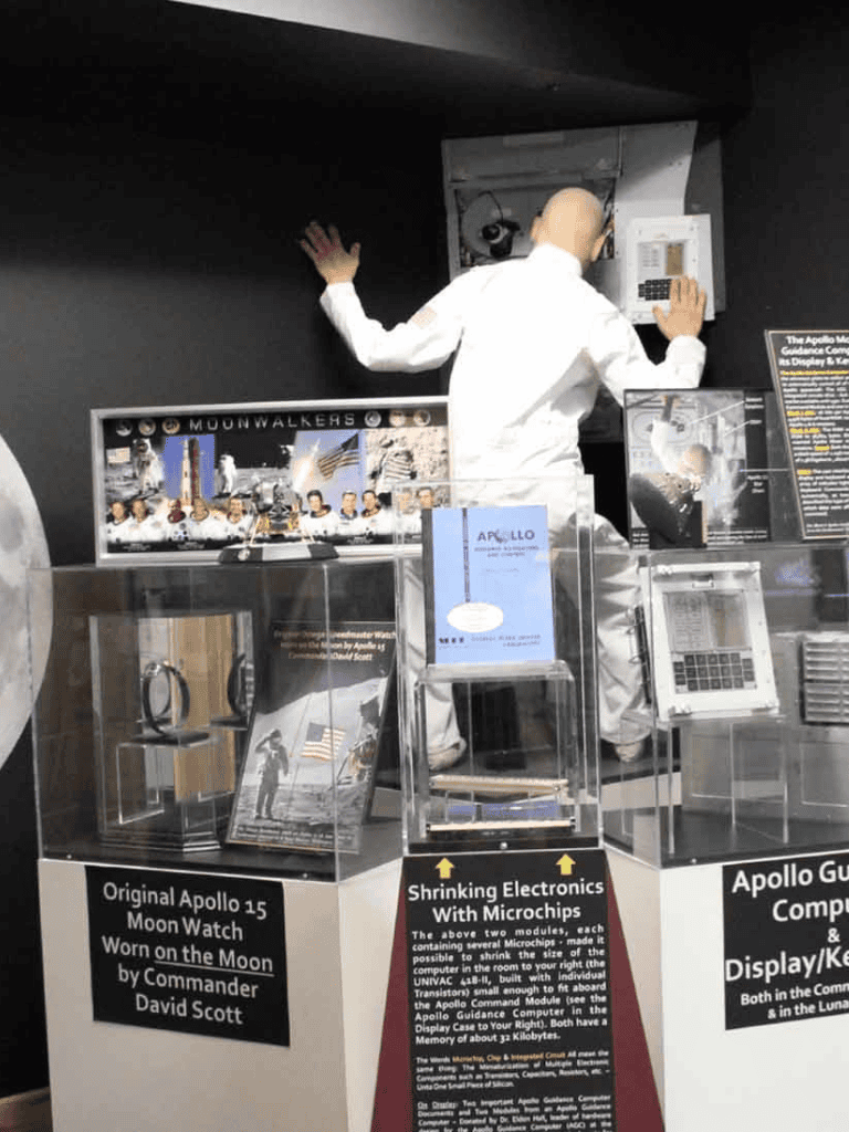Apollo 15 Moon Watch replica, astronaut helmet model, and vintage spacecraft display exhibit.