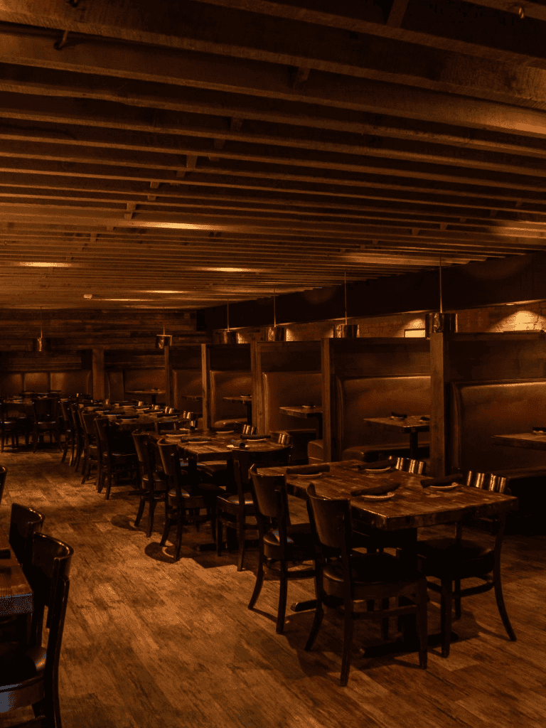 Cozy restaurant interior with wooden tables and warm lighting, ideal for dining and socializing.