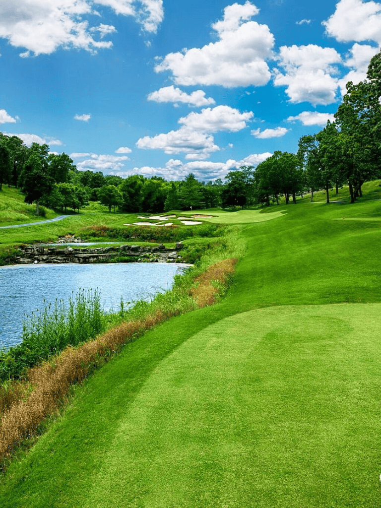 Lush green golf course with water hazard and scenic landscape, perfect for outdoor sports and recreation.