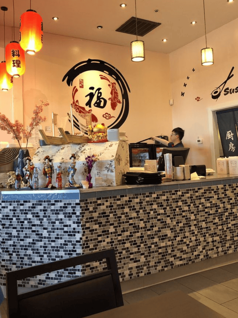 Bright Asian restaurant interior with decorative lanterns and wall art, featuring a tiled counter and traditional decor.