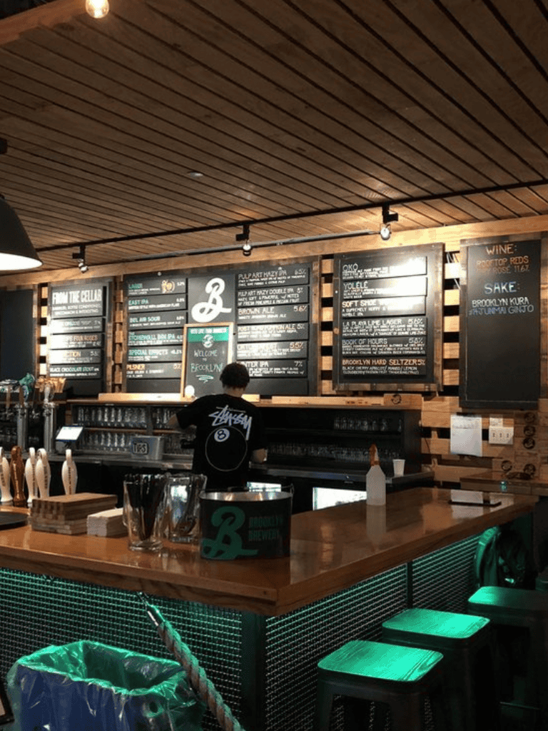 Bright bar interior with wooden accents, chalkboard menus, and neon lighting for craft cocktails and beers.