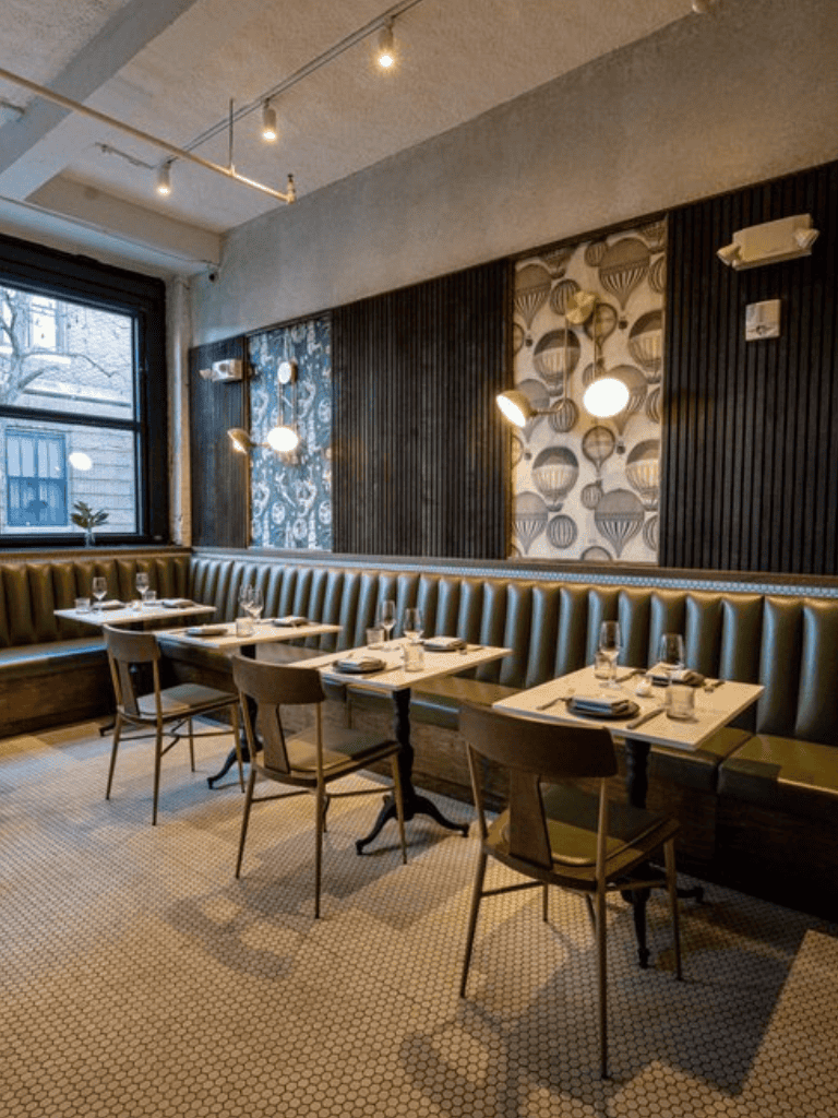 Cozy modern restaurant interior with stylish wall decor, pendant lighting, and neatly set tables for dining.