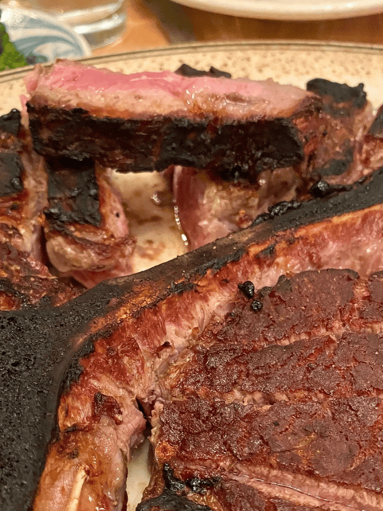 Juicy grilled steak with charred edges and perfect sear, served on a dinner plate.