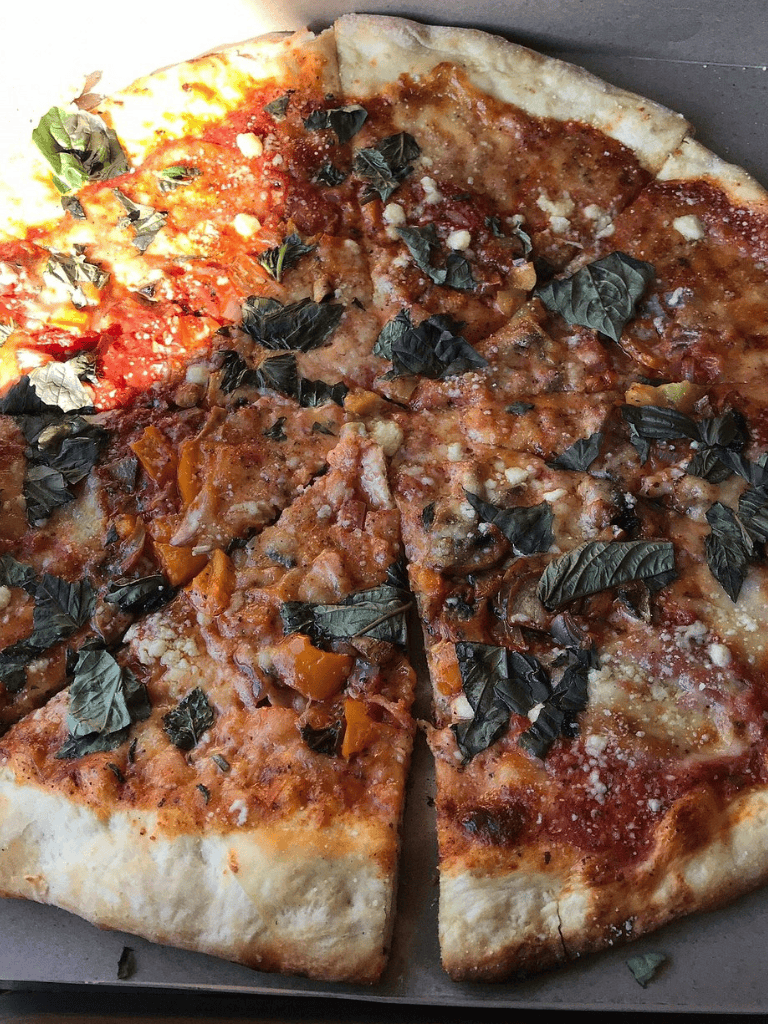 Neapolitan-style pizza with herbs, cheese, and tomato sauce.