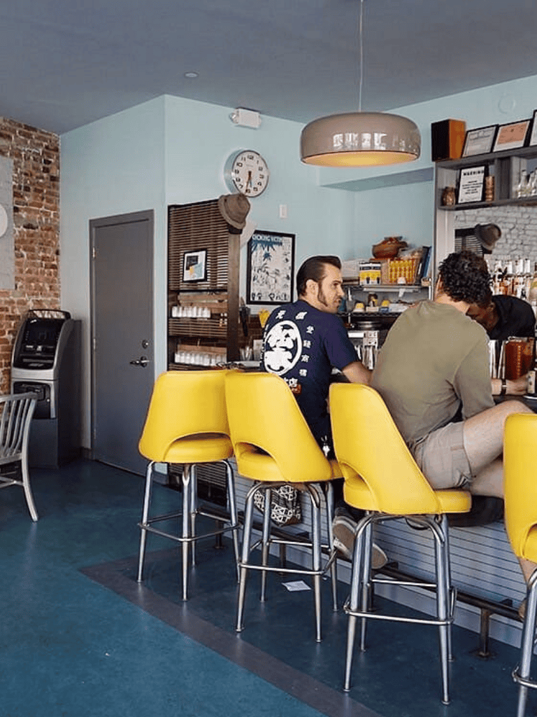 Bright interior of a trendy cafe with yellow chairs and a casual atmosphere, ideal for social gatherings and coffee dates.
