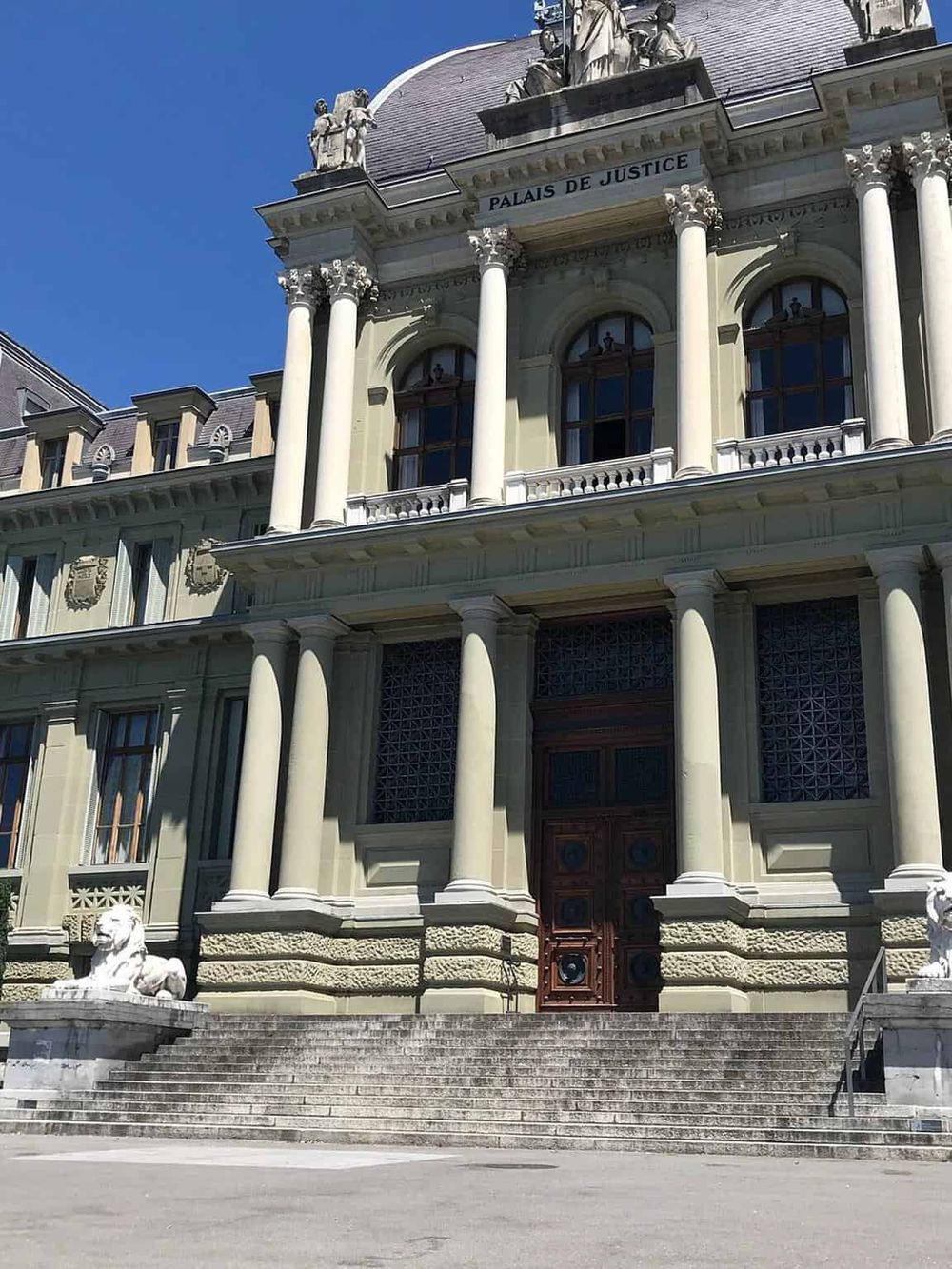 Grand historic justice palace with classical architecture, columns, and lion statues.