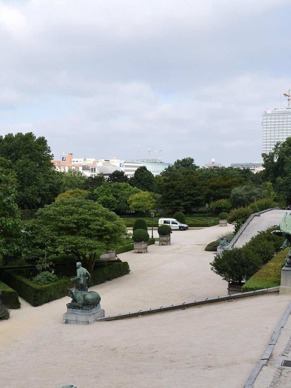 Serene park with sculptures, lush greenery, and cityscape views, ideal for relaxing and exploring nature.