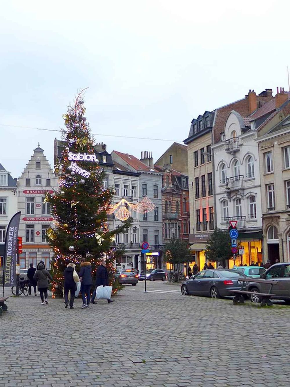 Colorful Christmas tree in a European city square during winter festival.