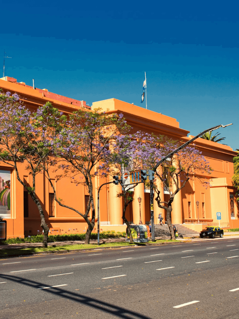 Colorful building with purple flowering trees and clear blue sky, downtown location, QuestForDirections.