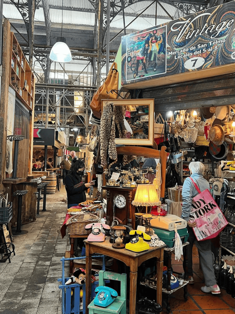 Vintage market stall with antique decor and retro accessories, bustling outdoor shopping scene.
