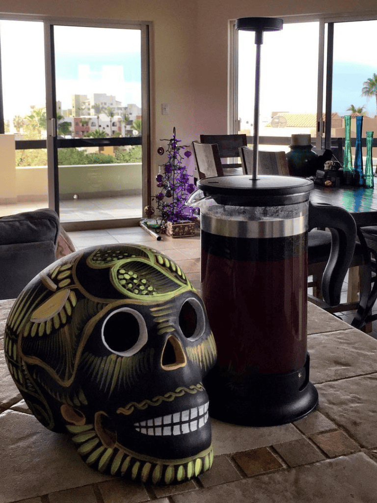 Colorful decorative sugar skull with coffee on a dining table, bright room, balcony view, QuestForDirections Interior.