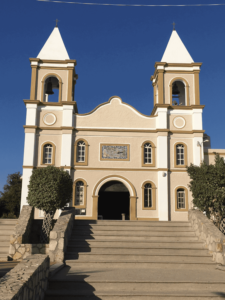 Ornate church with twin bell towers, set against a clear blue sky, featuring classic architecture.