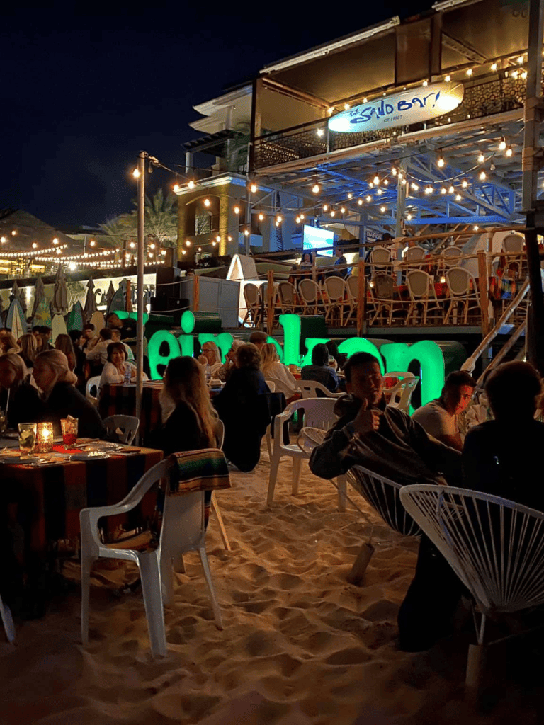 Night beachside dining with lively music and string lights at Snubar beach bar and restaurant.