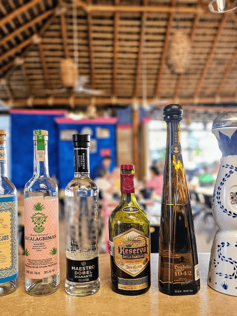 1. Assorted tequila bottles on rustic bar counter in a Mexican restaurant.