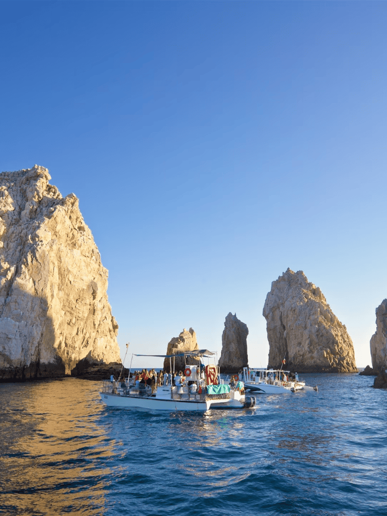 Stunning boat cruise near towering sea stacks on clear blue ocean water in scenic coastal landscape.