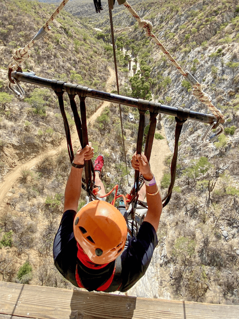 Adventurous zip line ride over rugged canyon terrain.