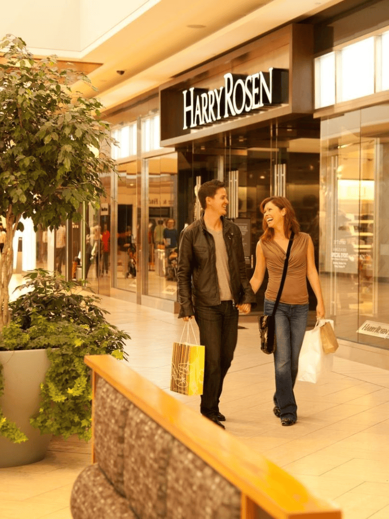 Happy couple shopping at Harry Rosen in a mall shopping center, enjoying their retail therapy.