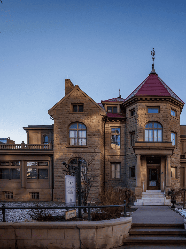 1. Victorian-style historic mansion with stone architecture and red roof, located in a city setting.