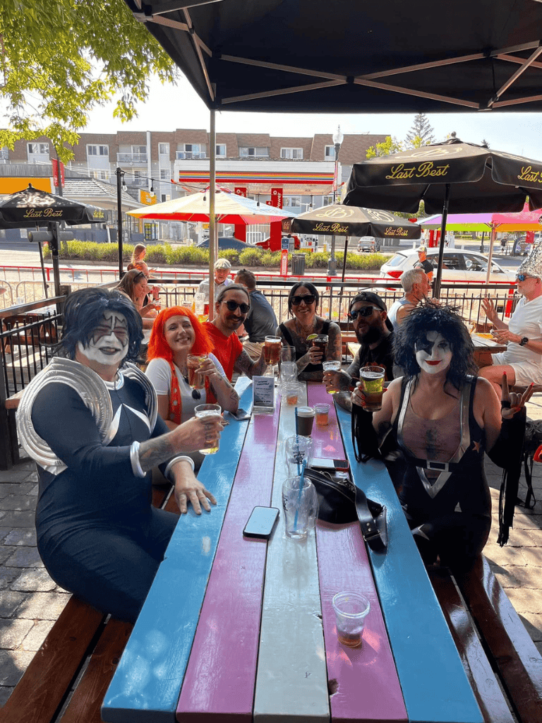 Lively outdoor restaurant scene with people dressed as KISS band members on a colorful patio.