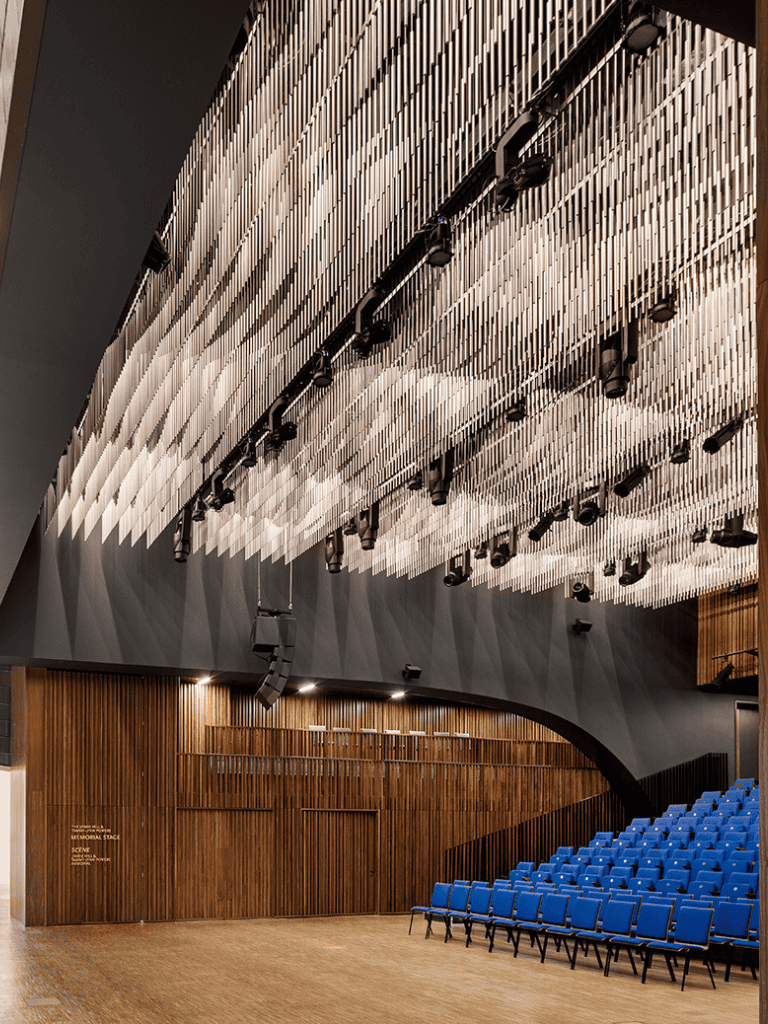Modern theater interior with acoustic ceiling panels and blue seating, ideal for performances and events.