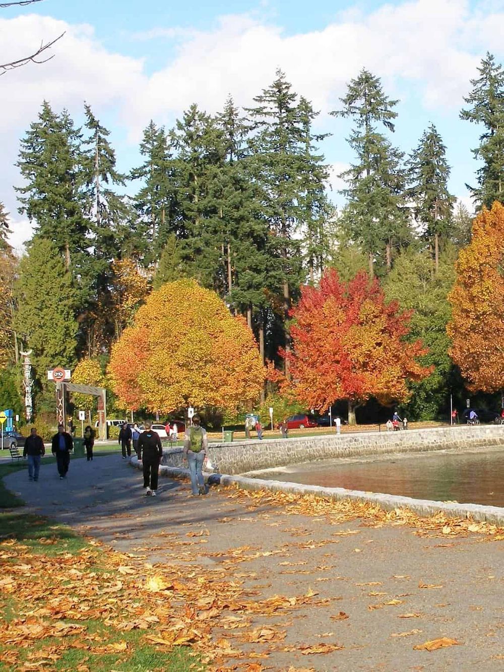 Colorful fall trees and a scenic lakeside walkway in a park setting.