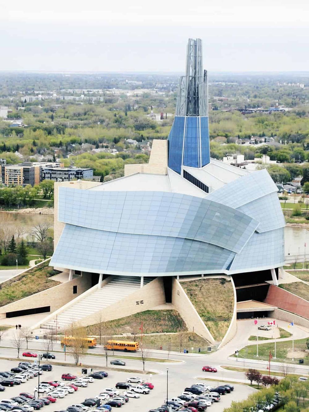 Modern chapel with unique architectural design and glass features, set in a scenic cityscape with greenery and parking area.