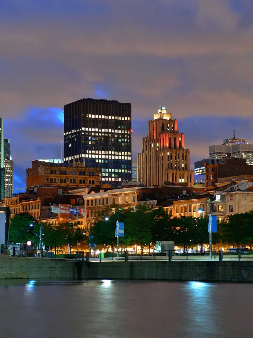 Bright city skyline at night with illuminated skyscrapers and waterfront view, showcasing urban cityscape and night lights.