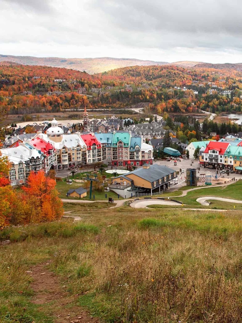 Vibrant autumn scene of a resort town with colorful buildings, scenic mountains, and fall foliage.