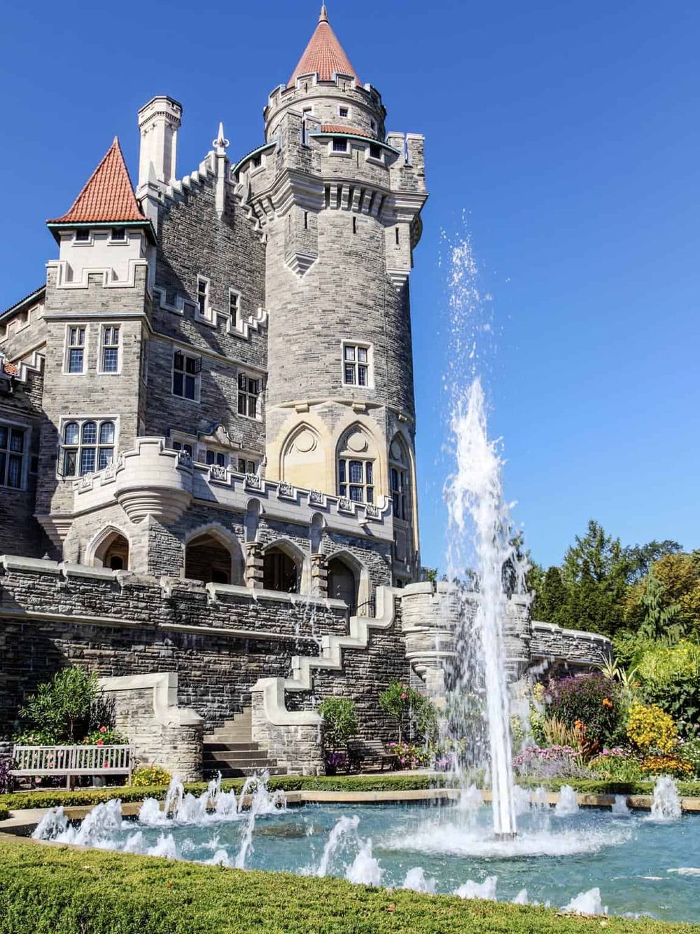 Majestic castle with fountain and colorful garden on a bright, sunny day in the castle park.