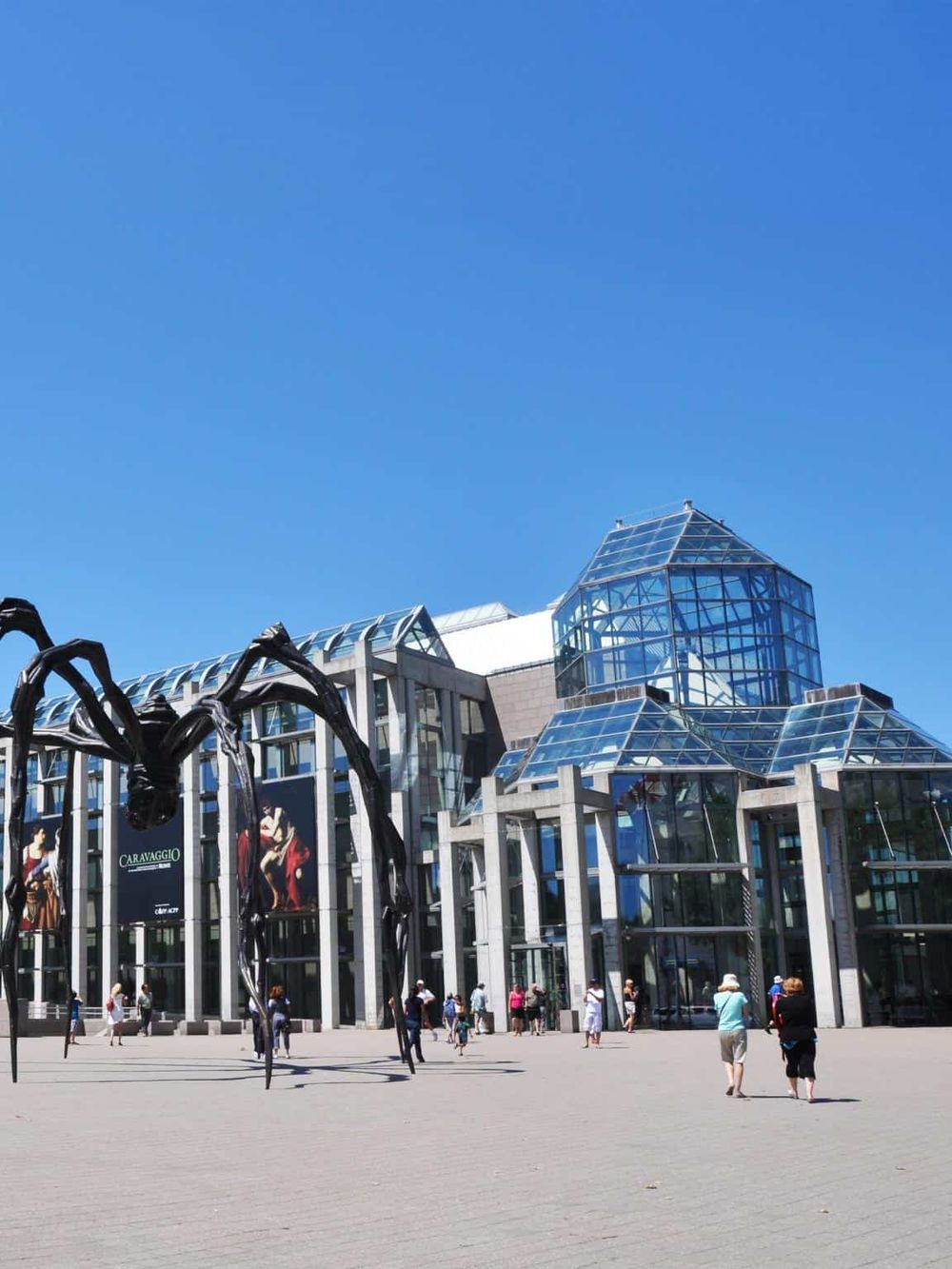 Modern glass museum building with outdoor spider sculpture at QuestForDirections.