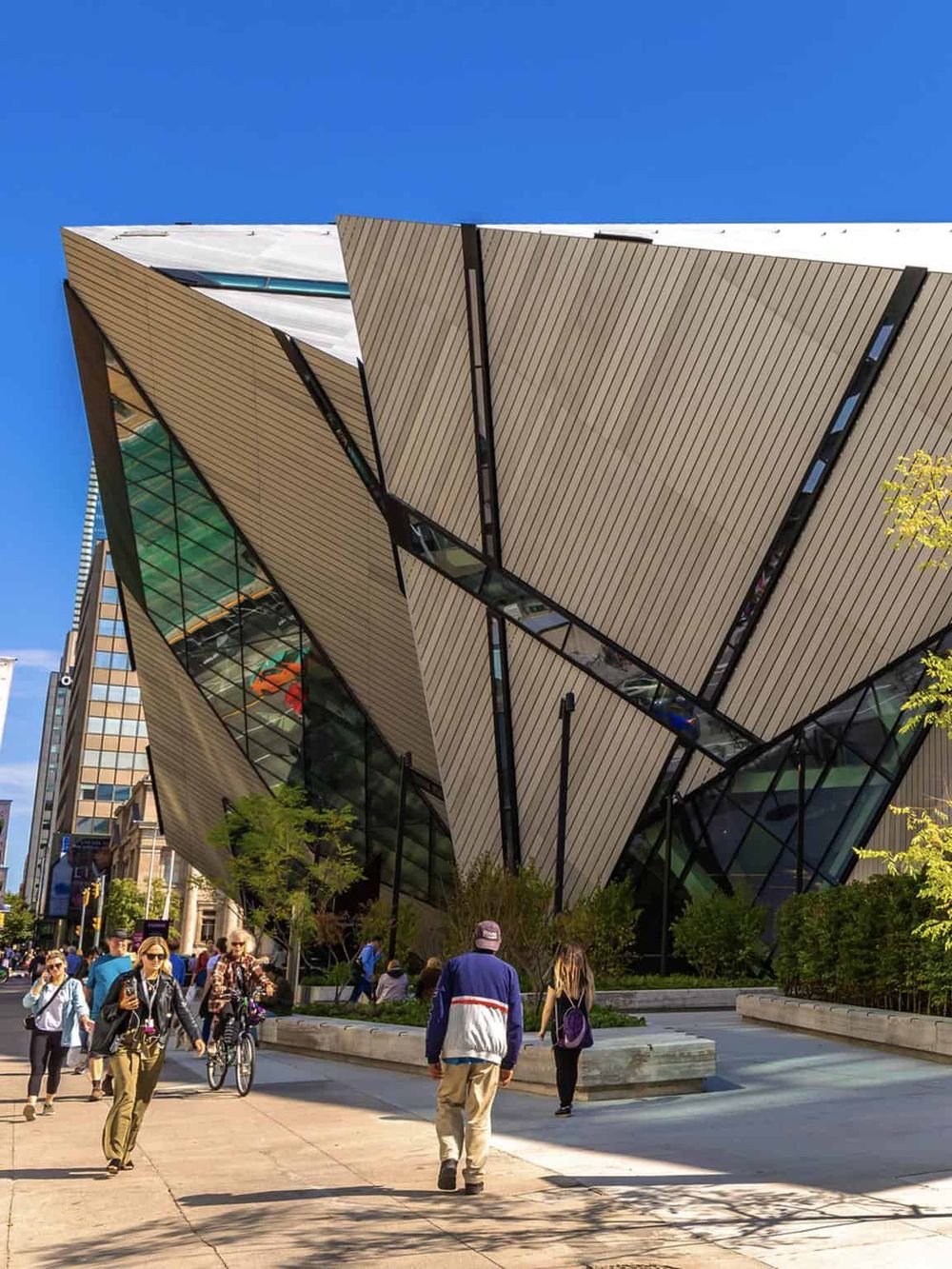 Futuristic architectural building with people walking and cycling on city street, QuestForDirections.