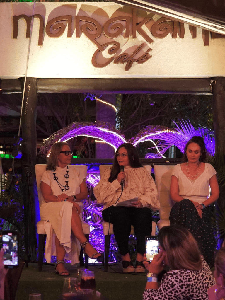 Women panel discussion at Marakan Cafe with purple lighting and audience members capturing the moment.