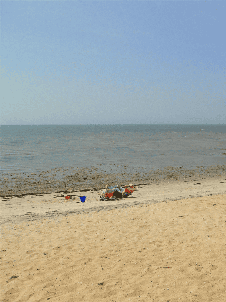 1. Beach scene with sand, ocean, and two lounge chairs, peaceful seaside escape.